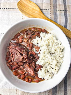 Slow Cooker Red Beans served in a white bowl garnished with fresh herbs and a side of rice, illustrating the final delicious meal made from the recipe.