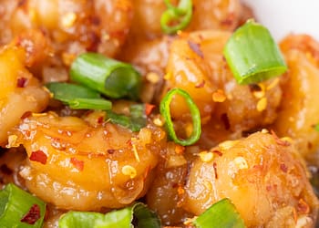 Plump shrimp bathed in a glossy honey garlic sauce, topped with crisp green onions and fiery red pepper flakes.