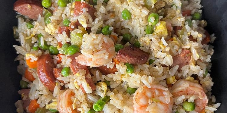 A colorful plate of Cajun Fried Rice loaded with Andouille sausage, shrimp, and vibrant vegetables, garnished with fresh green onions