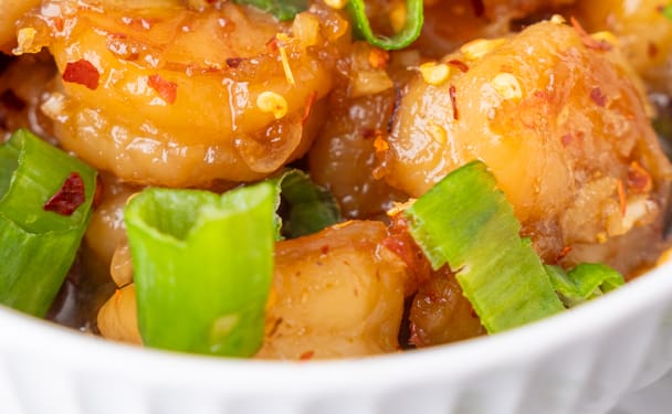 Plump shrimp bathed in a glossy honey garlic sauce, topped with crisp green onions and fiery red pepper flakes.