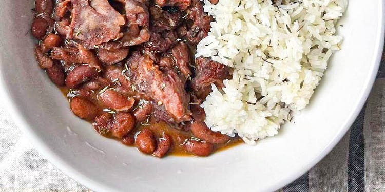 Slow Cooker Red Beans served in a white bowl garnished with fresh herbs and a side of rice, illustrating the final delicious meal made from the recipe.