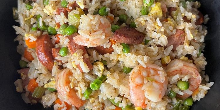 A colorful plate of Cajun Fried Rice loaded with Andouille sausage, shrimp, and vibrant vegetables, garnished with fresh green onions