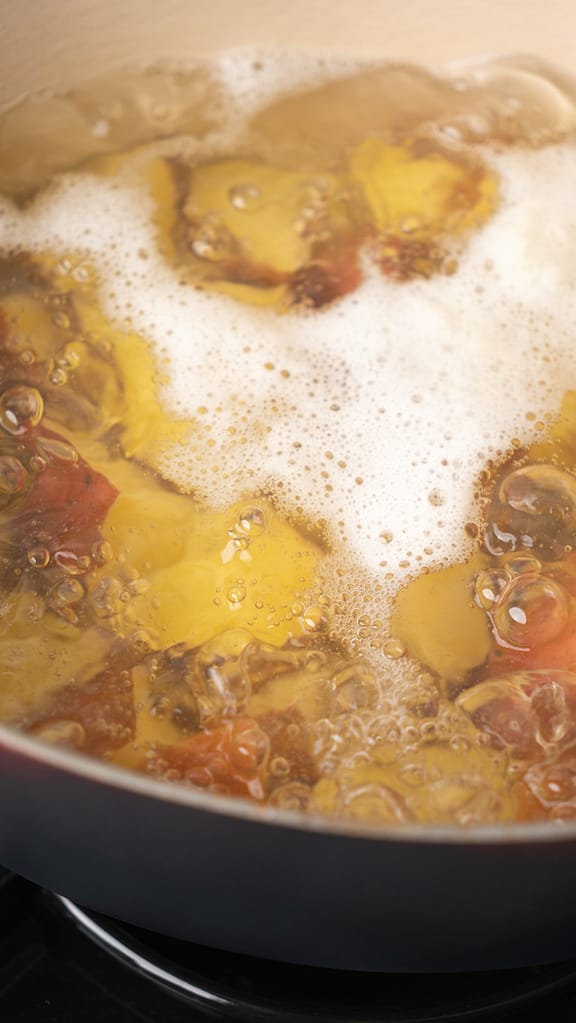 Red potatoes boiling in a pot of water, preparing for garlic mashed potato recipe