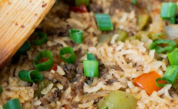 Cajun Dirty Rice in a cast iron skillet with a wooden spoon