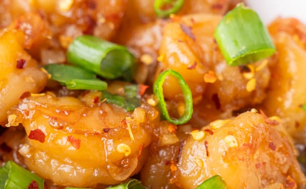 Plump shrimp bathed in a glossy honey garlic sauce, topped with crisp green onions and fiery red pepper flakes.