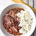 Slow Cooker Red Beans served in a white bowl garnished with fresh herbs and a side of rice, illustrating the final delicious meal made from the recipe.