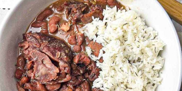 Slow Cooker Red Beans served in a white bowl garnished with fresh herbs and a side of rice, illustrating the final delicious meal made from the recipe.